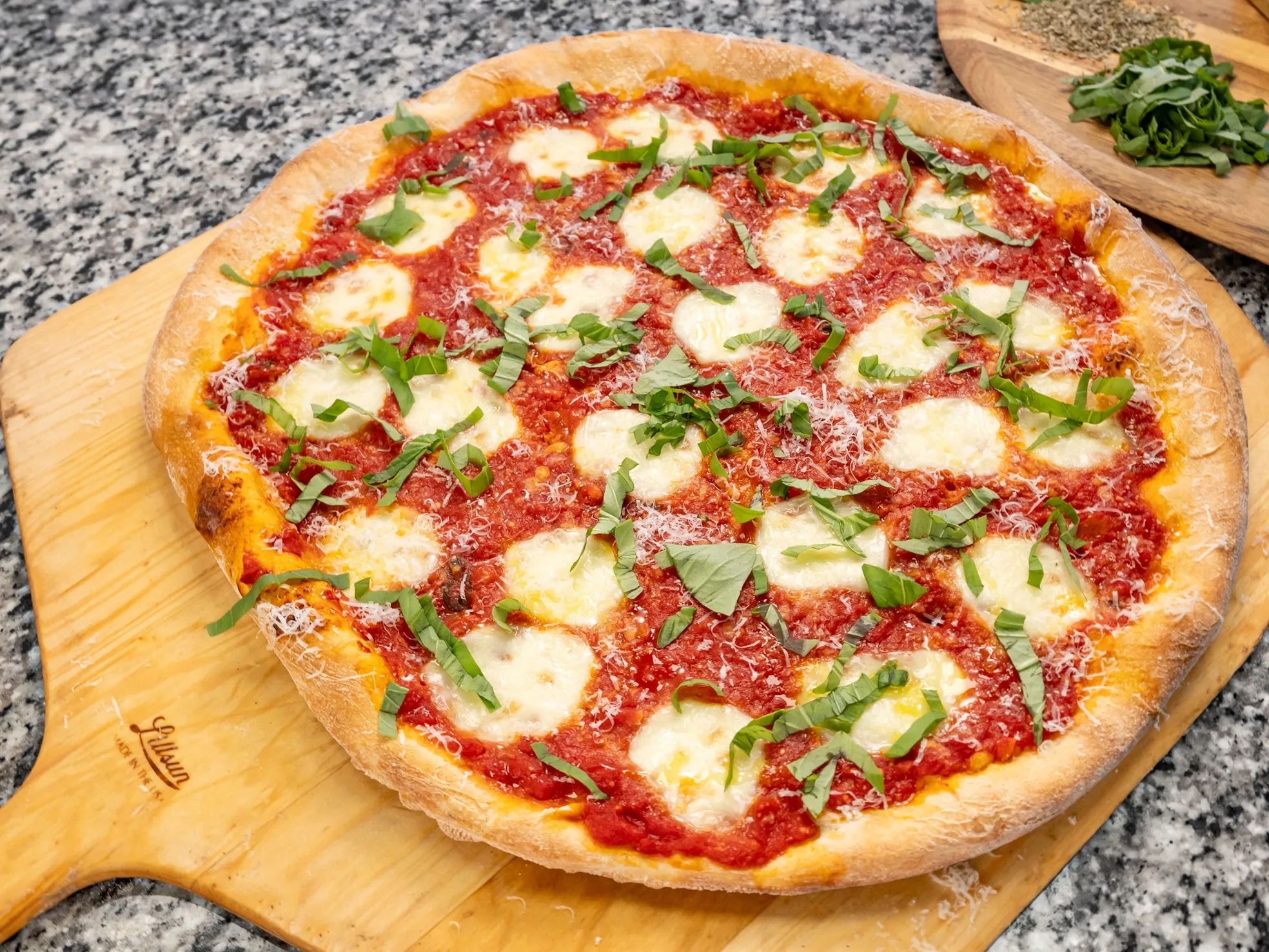 Fresh margherita pizza with mozzarella, basil and parmesan on a wooden peel